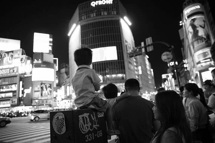 WOMAN STANDING IN ILLUMINATED CITY AT NIGHT