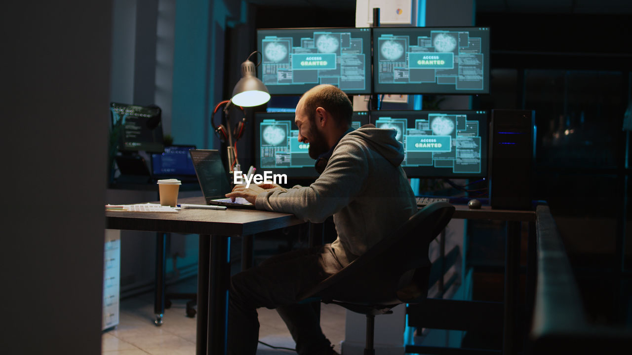 man using laptop at desk in office