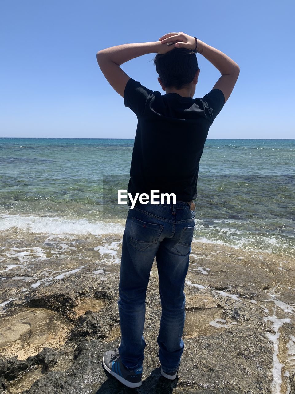 REAR VIEW OF PERSON STANDING ON BEACH