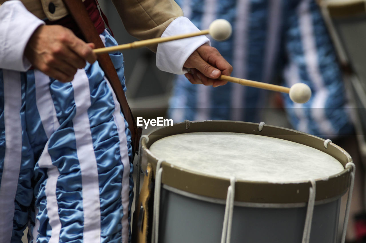 Midsection of man playing drum in city