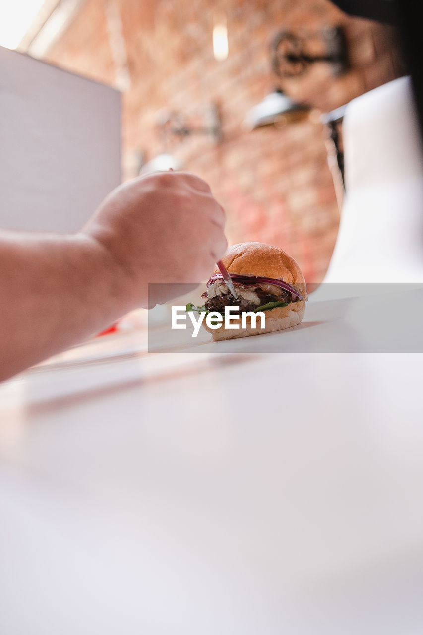 Close-up of hand preparing a burger