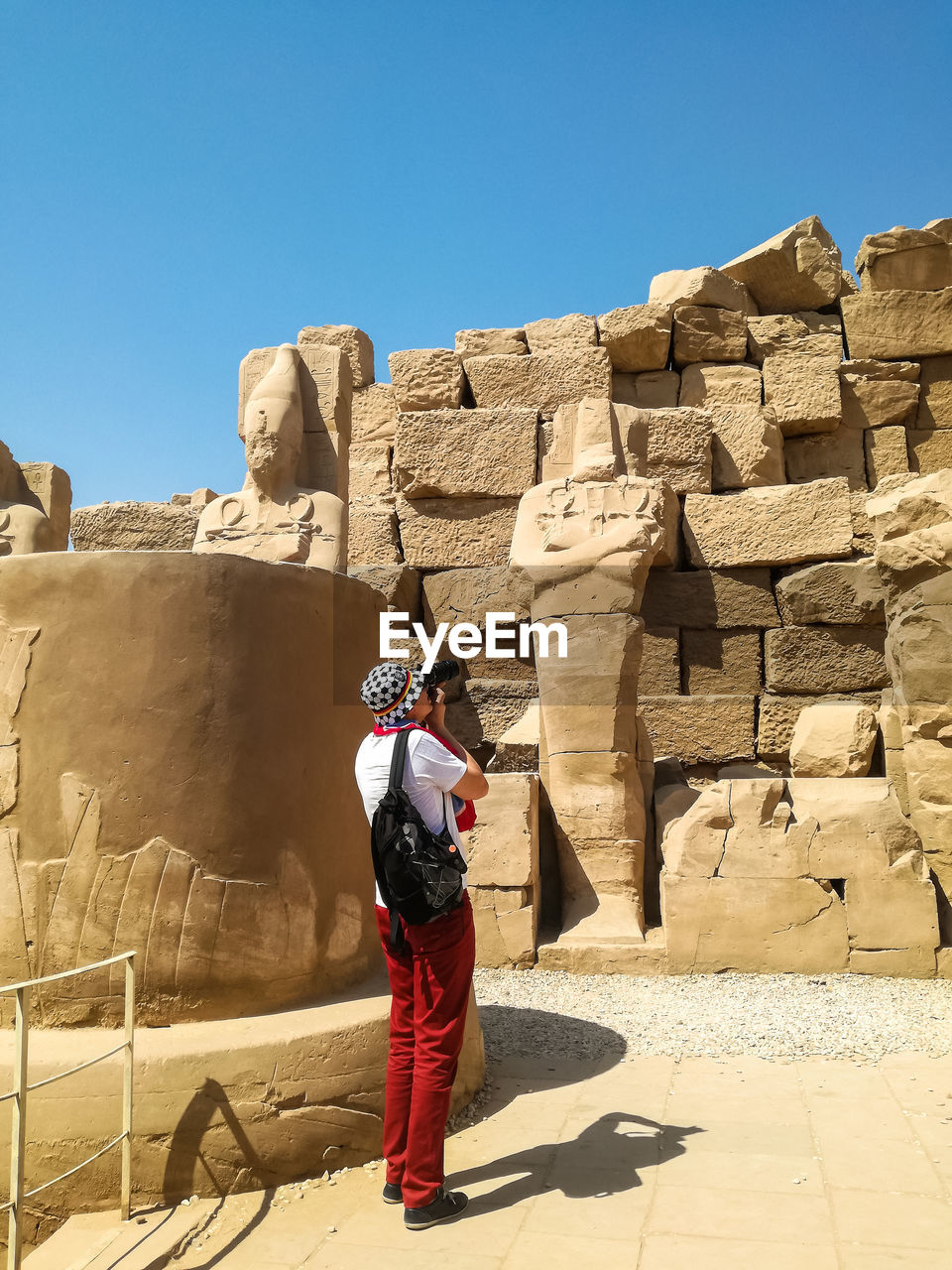 Tourist among ancient ruins. one man on excursion to karnak temple photographs sights. luxor, egypt