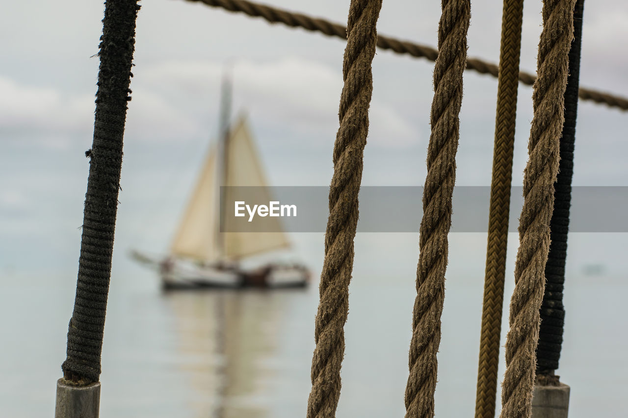 Close-up of rope on sailboat - ship sailing on the ocean behind - selective focus