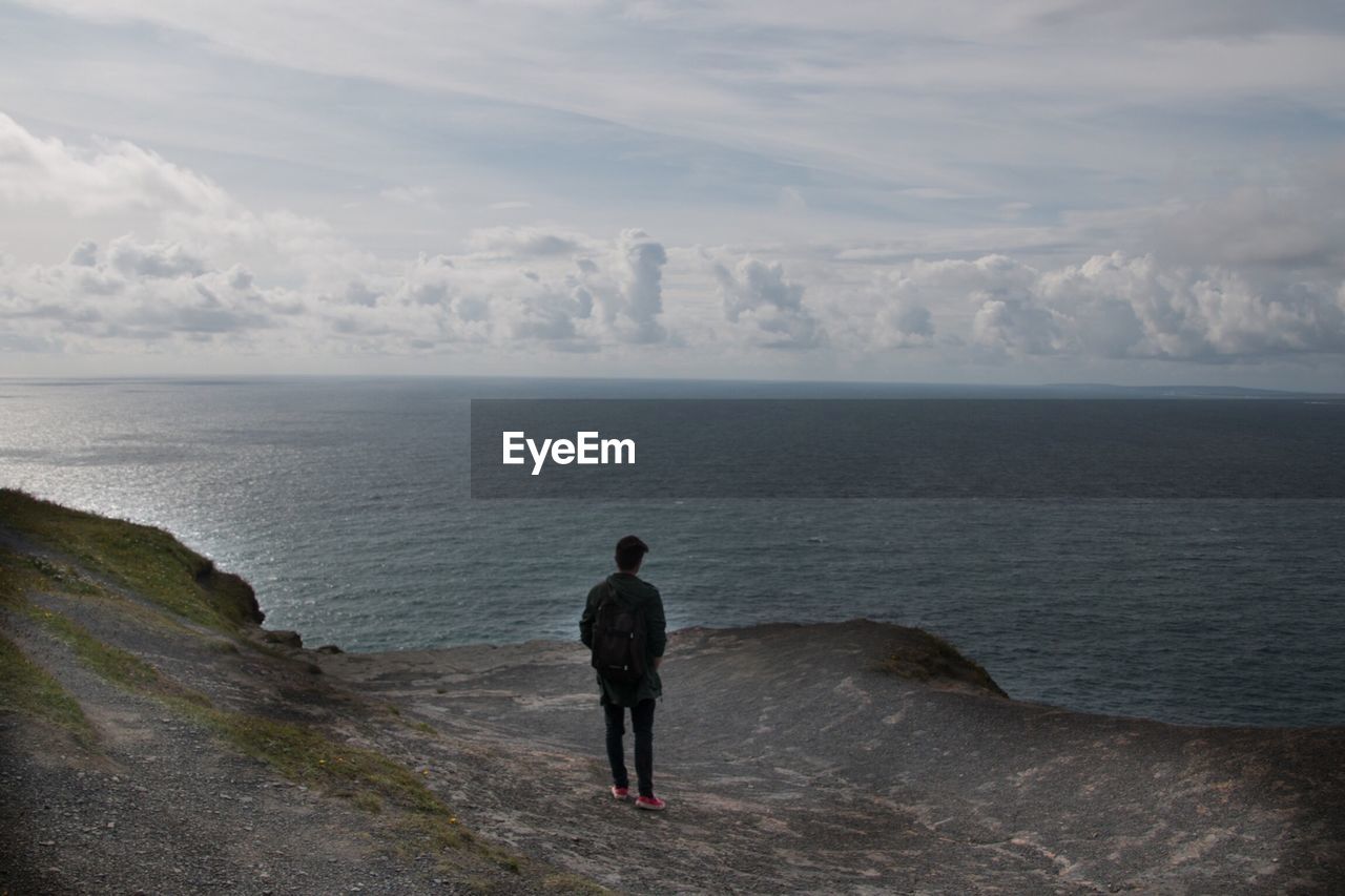 Rear view of a man overlooking calm sea