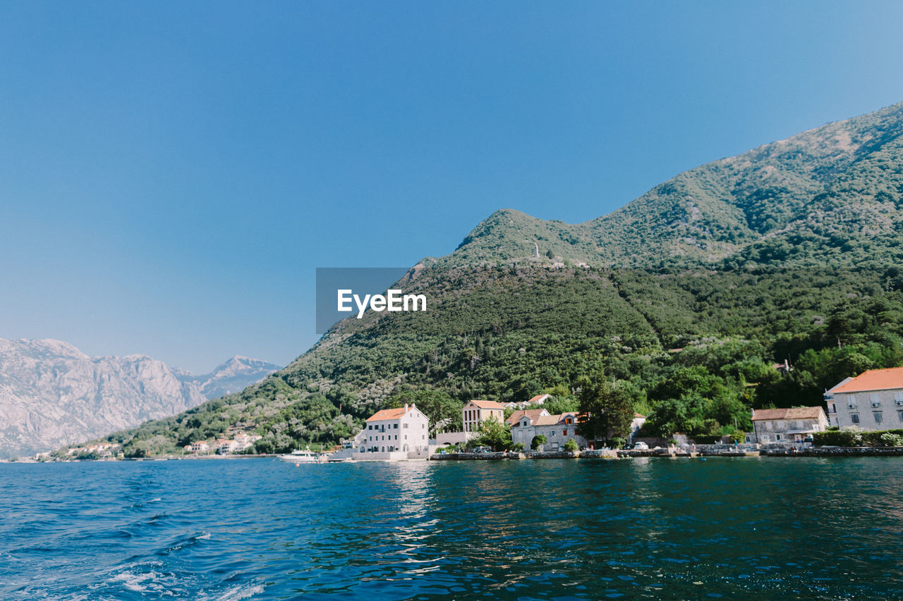 Scenic view of sea and mountains against clear blue sky