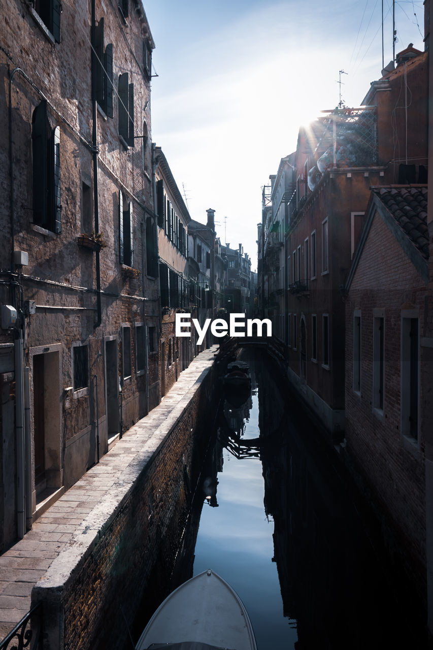 Canal amidst buildings against sky