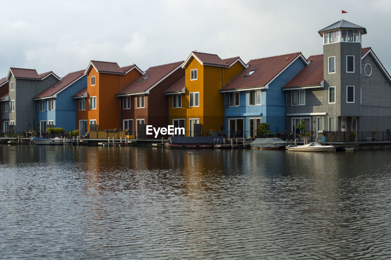 Buildings by river against sky in city