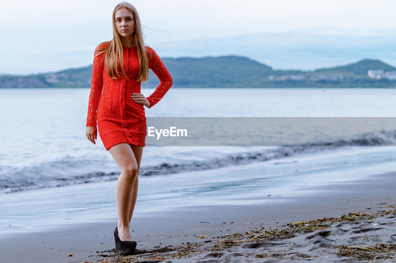 FULL LENGTH PORTRAIT OF YOUNG WOMAN AT BEACH