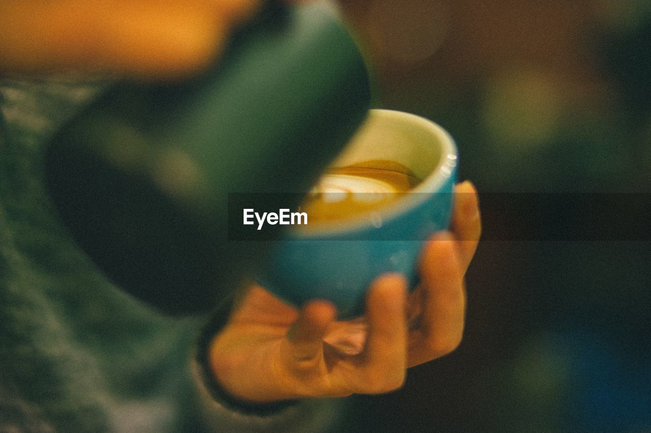 Close-up of hand pouring coffee in cup