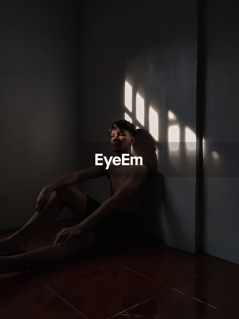 YOUNG MAN LOOKING AWAY WHILE SITTING IN WALL