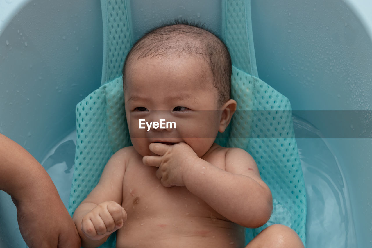 Cute baby girl lying in container