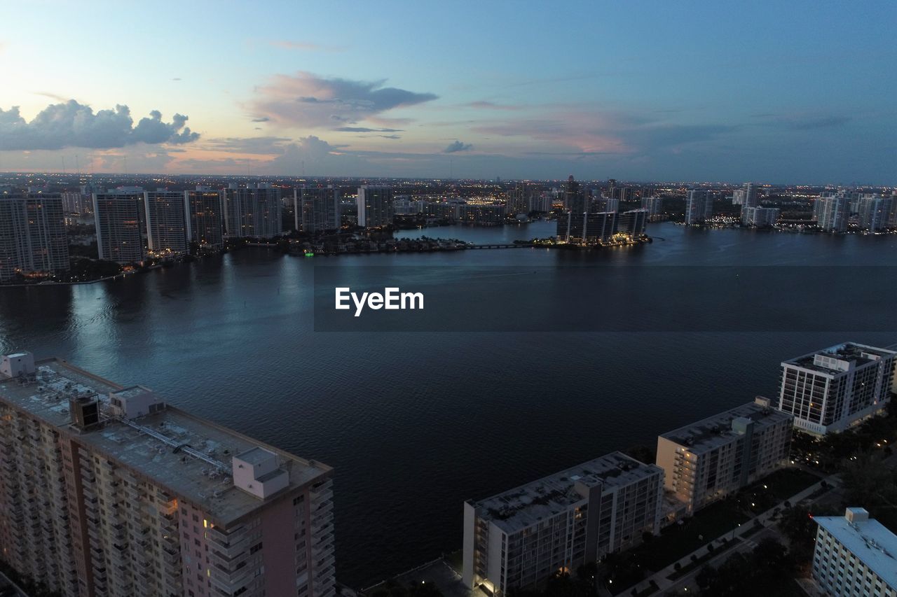 High angle view of buildings by sea against sky during sunset