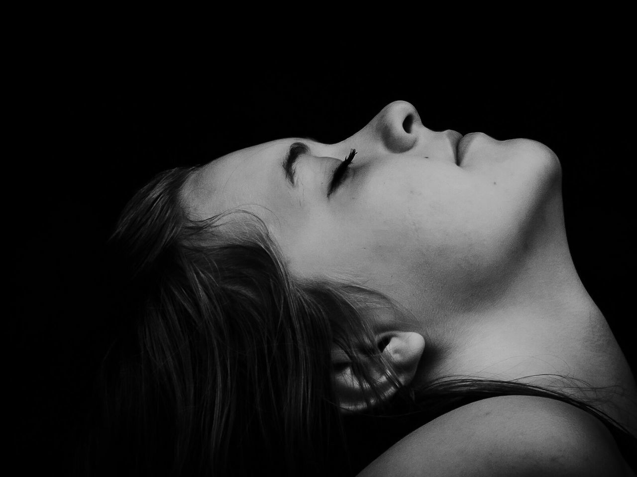 Close-up of woman with eyes closed against black background
