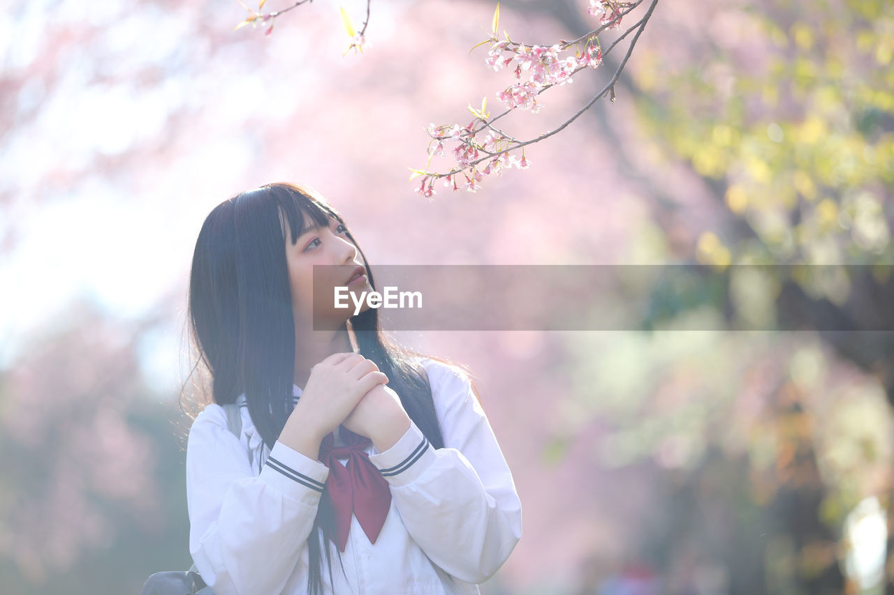 YOUNG WOMAN STANDING ON CHERRY BLOSSOM