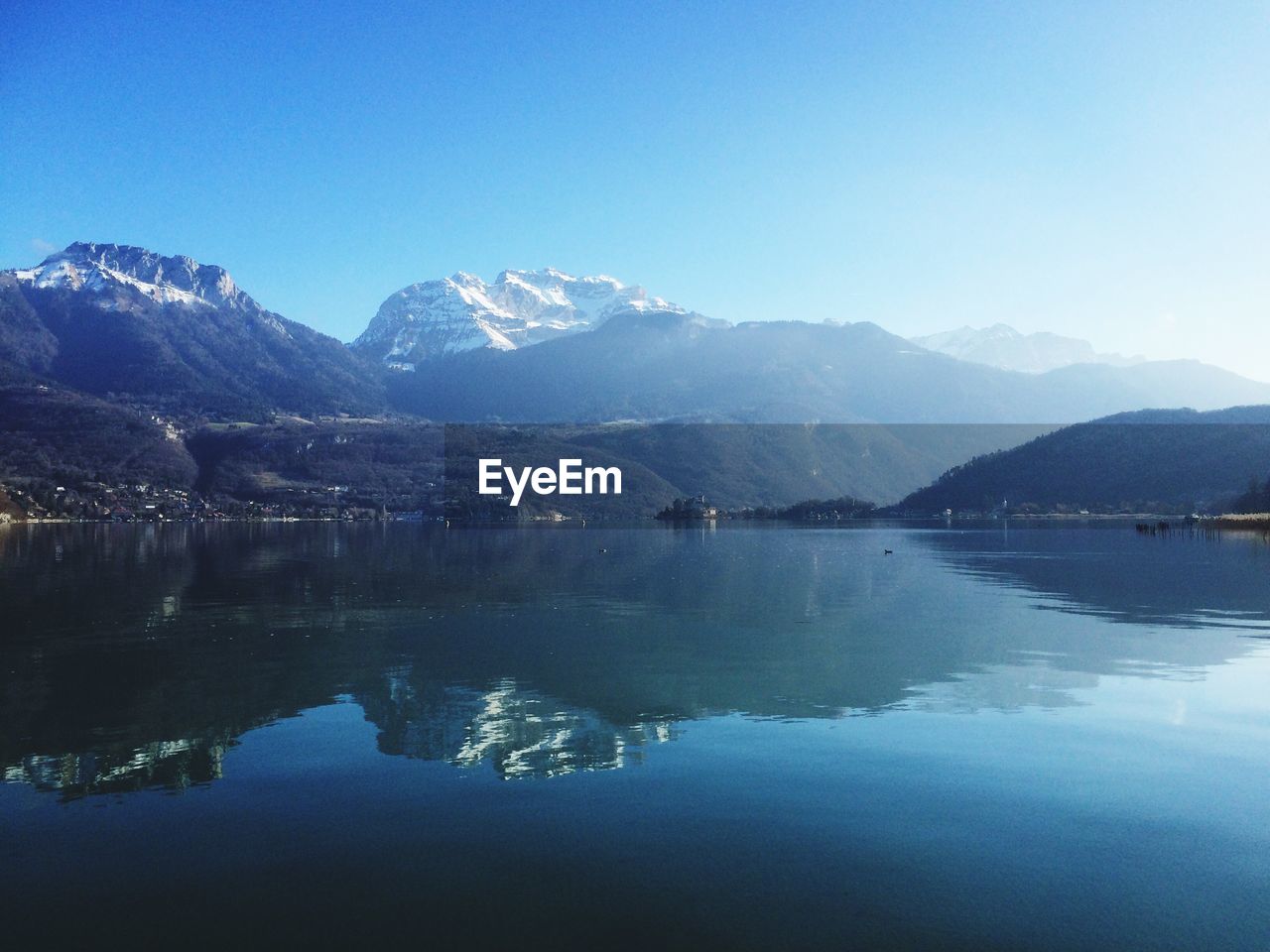 Scenic view of lake and mountains against clear blue sky