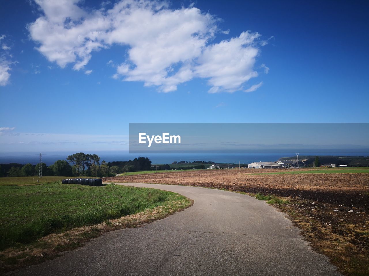 ROAD PASSING THROUGH FIELD AGAINST SKY