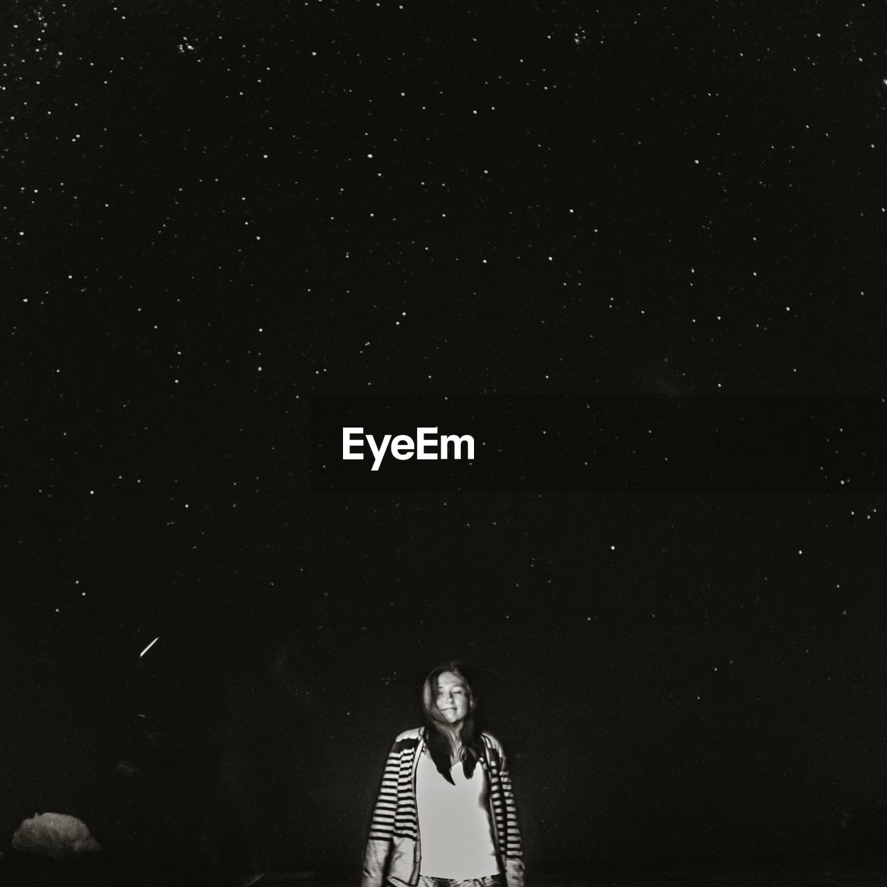Girl meditating and closing her eyes with the stars shining above