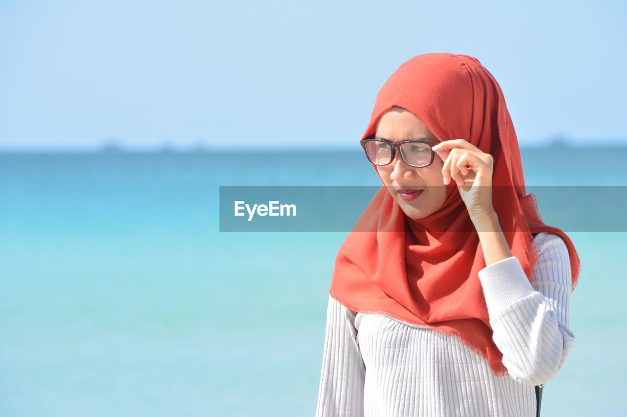 Woman wearing hijab while standing against sea