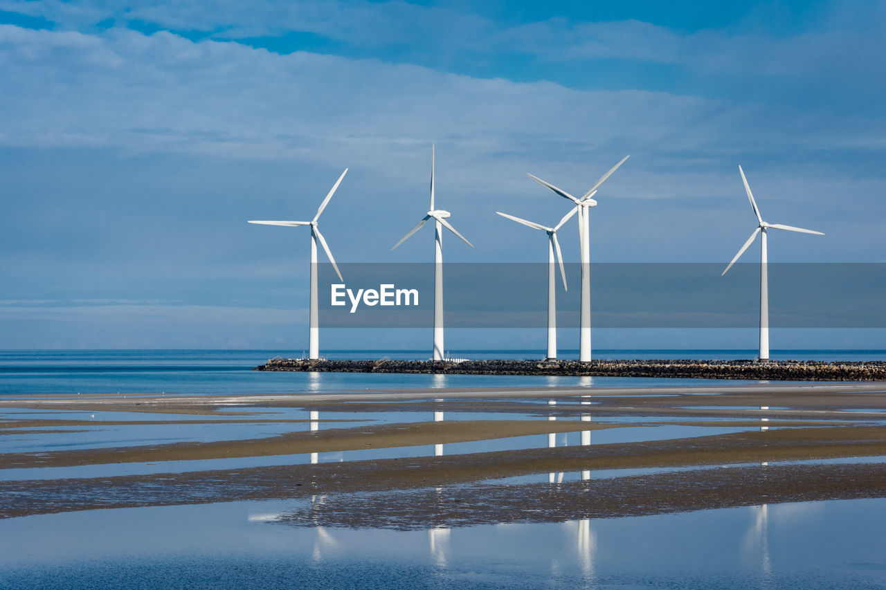 Wind turbines on sea shore against sky