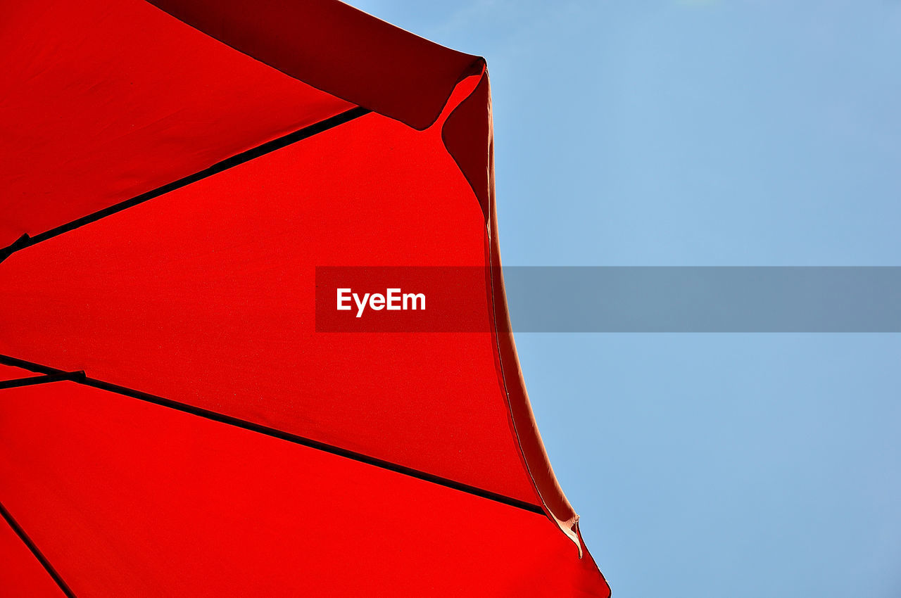 Low angle view of red umbrella against blue sky