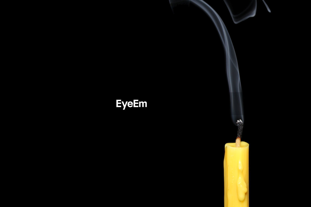 Close-up of candle and smoke against black background