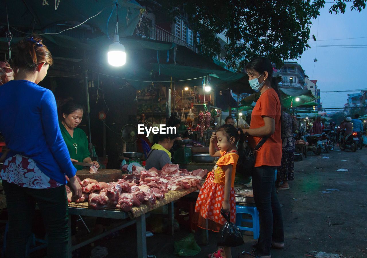 GROUP OF PEOPLE AT MARKET STALL AT NIGHT