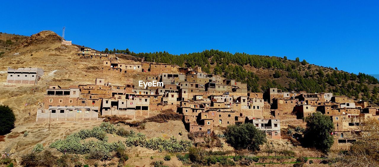 Low angle view of houses on mountain against clear blue sky