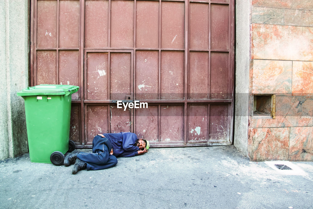 GARBAGE BIN ON FOOTPATH AGAINST BUILDING