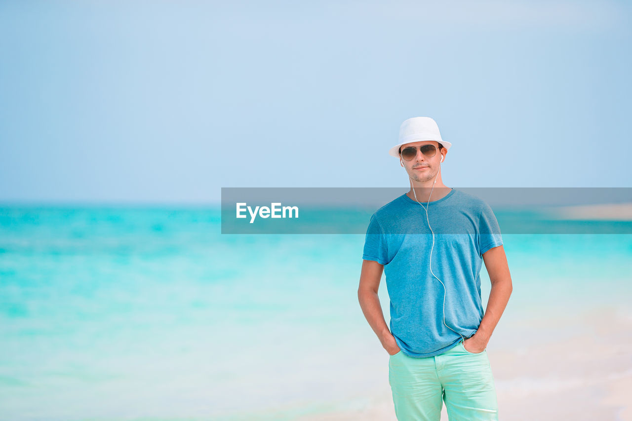 YOUNG MAN STANDING ON BEACH