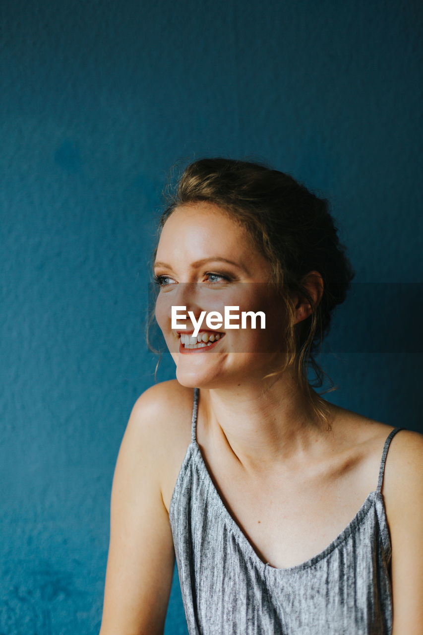 Portrait of smiling young woman against blue background