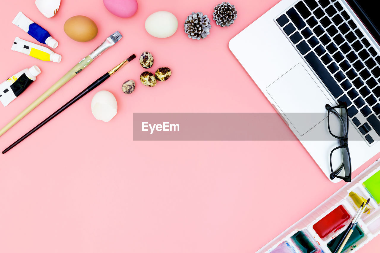 High angle view of laptop with decorations over colored background