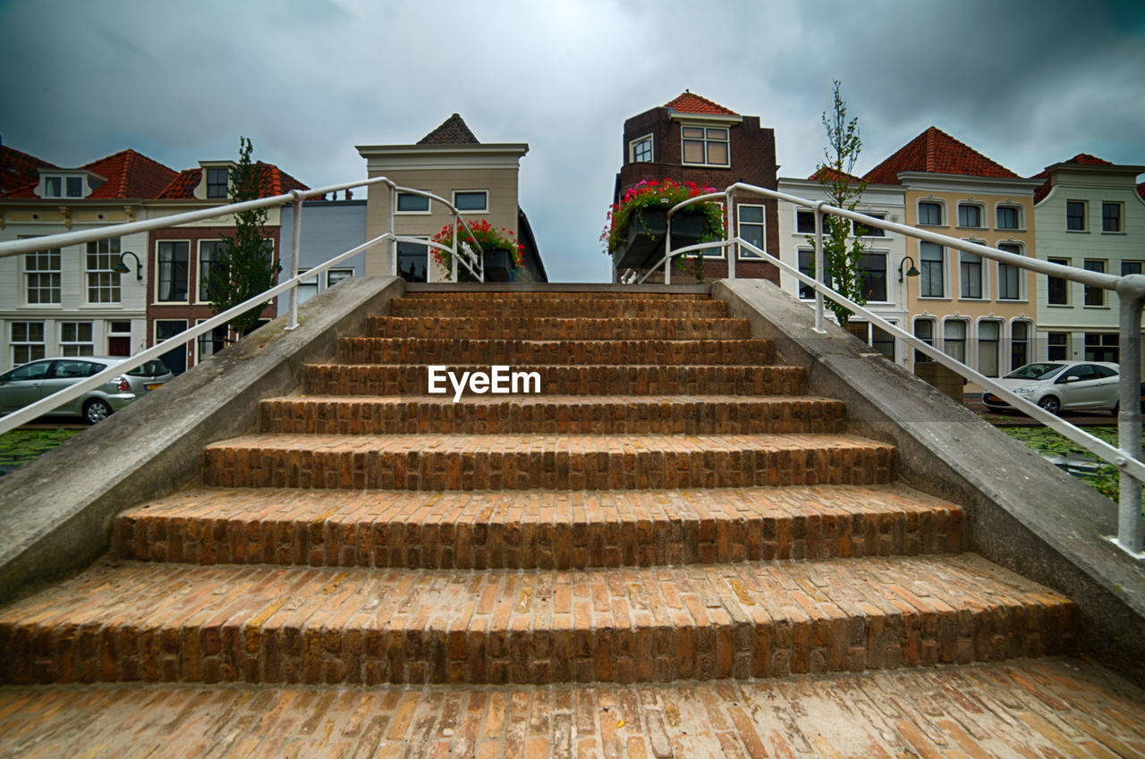 Low angle view of staircase amidst buildings against sky
