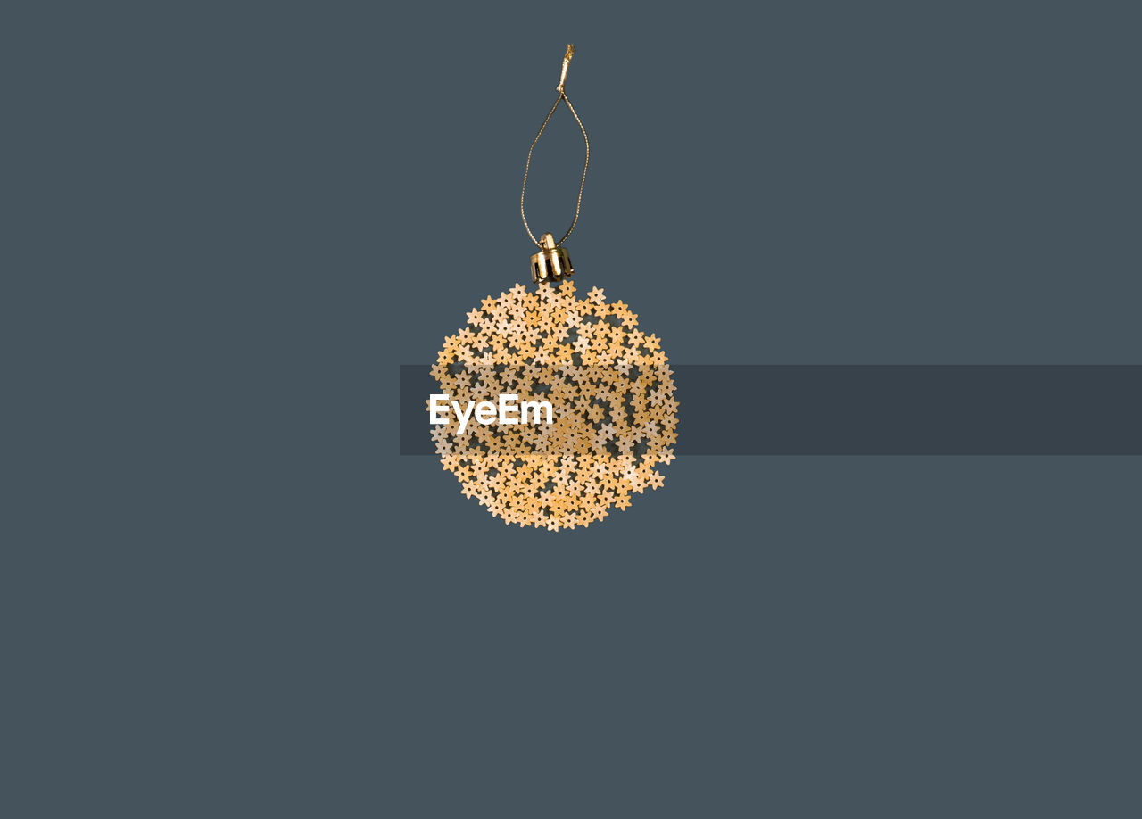 Christmas decoration on a tree in the form of a ball of pasta on a blue paper background, top view.