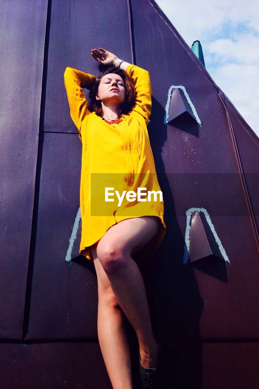 PORTRAIT OF YOUNG WOMAN STANDING ON WALL