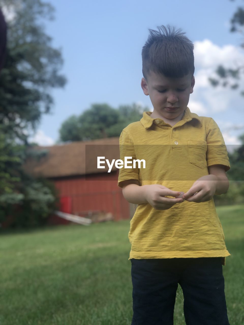 BOY STANDING ON FIELD AGAINST CLEAR SKY