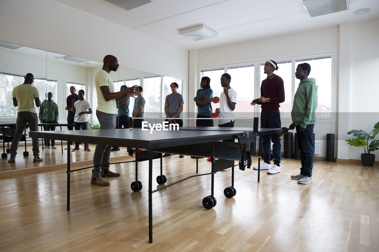 Coach giving table tennis instructions to students in games room