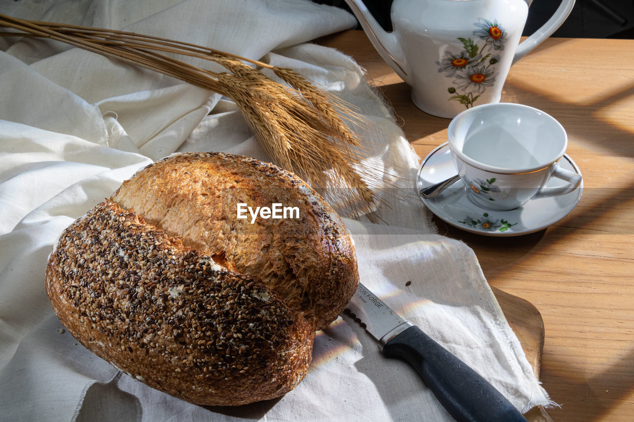 food and drink, food, bread, table, freshness, baked, breakfast, drink, cup, indoors, healthy eating, meal, eating utensil, high angle view, wellbeing, mug, no people, still life, kitchen utensil, coffee, wood, refreshment, loaf of bread, spoon, cereal plant, close-up, dessert, dish, knife