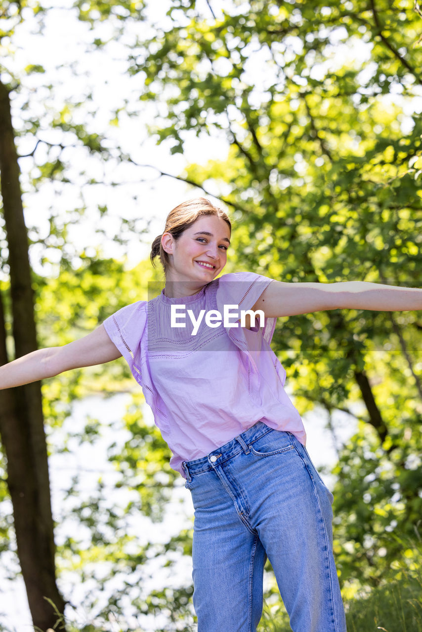 full length of young woman standing against trees