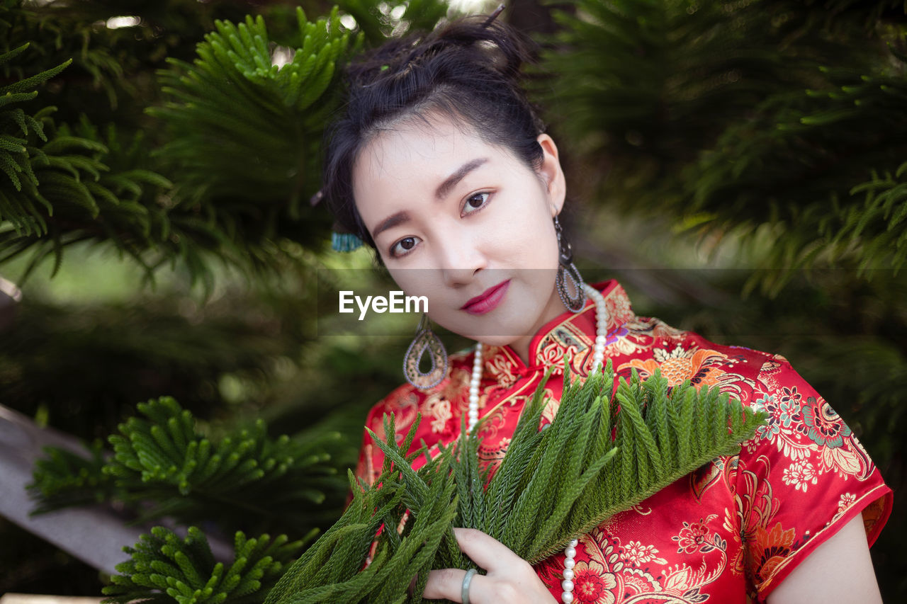 Portrait of smiling woman in traditional clothes standing by plant