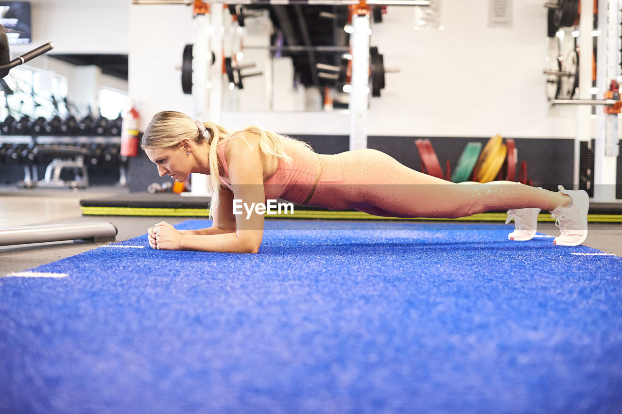 A fit female doing a forearm plank in the gym.