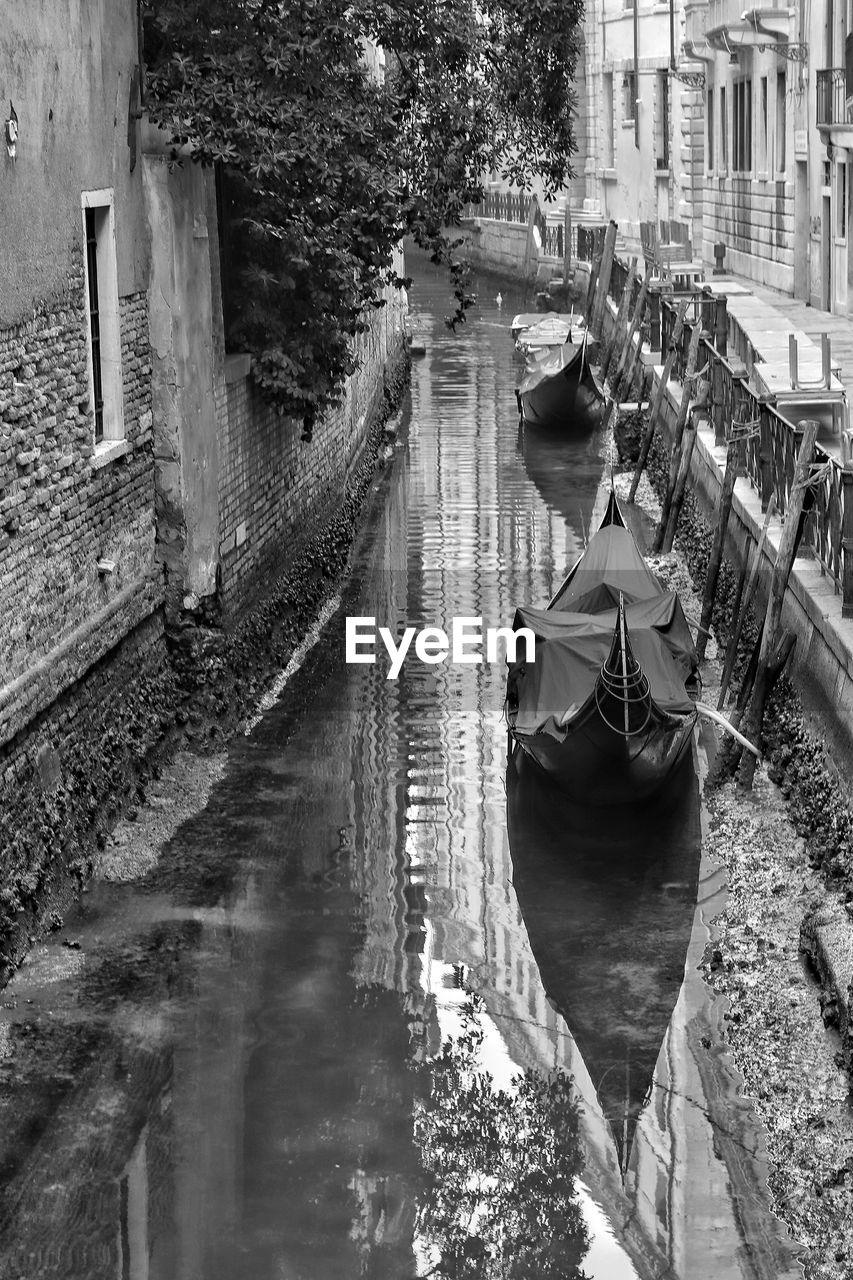 REAR VIEW OF MAN ON CANAL BY BUILDINGS