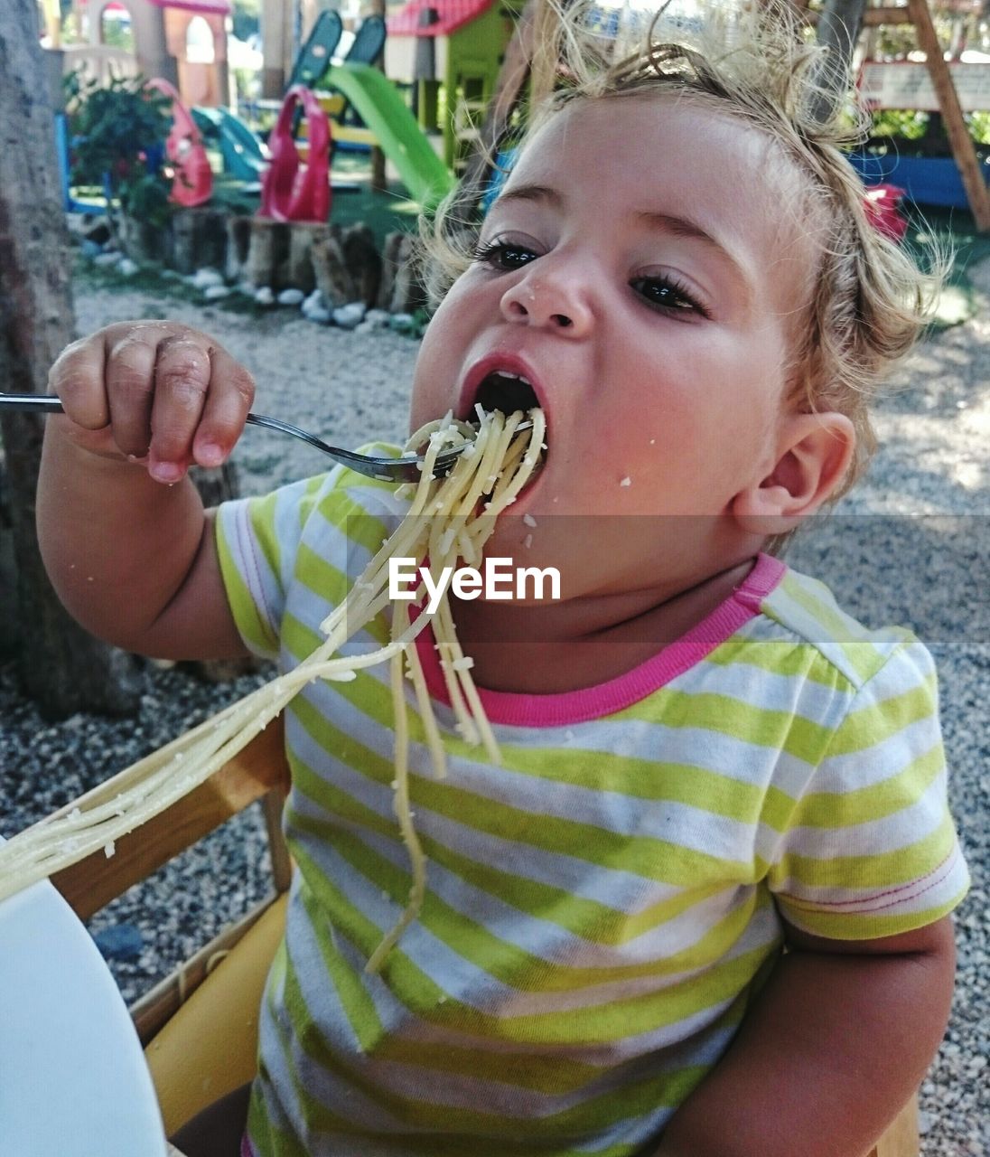 High angle view of child eating spaghetti in plate at park