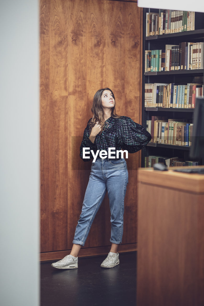 Young woman looking away while standing in library