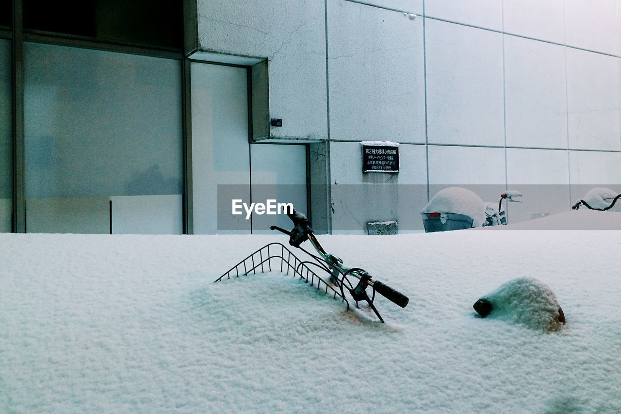 Bicycles covered in snow against building