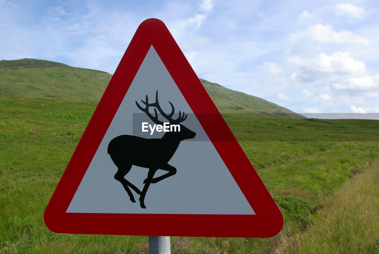 CLOSE-UP OF ROAD SIGN ON LANDSCAPE