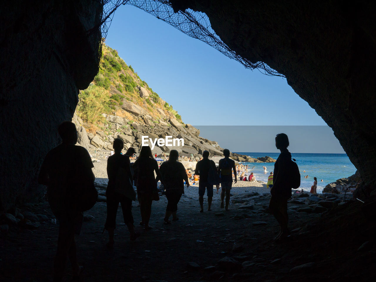 Silhouette people under cave at beach