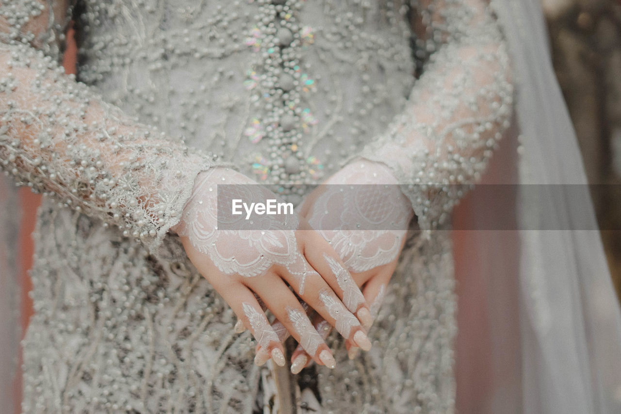 wedding dress, dress, wedding, women, adult, bride, midsection, one person, newlywed, clothing, life events, celebration, lace, event, hand, lace - textile, pattern, gown, fashion, bridal clothing, jewelry, fashion accessory, focus on foreground, close-up, wedding ceremony, love, young adult, holding, ring, positive emotion, married, textile, standing, ceremony, emotion, day, indoors, lifestyles, spring, front view