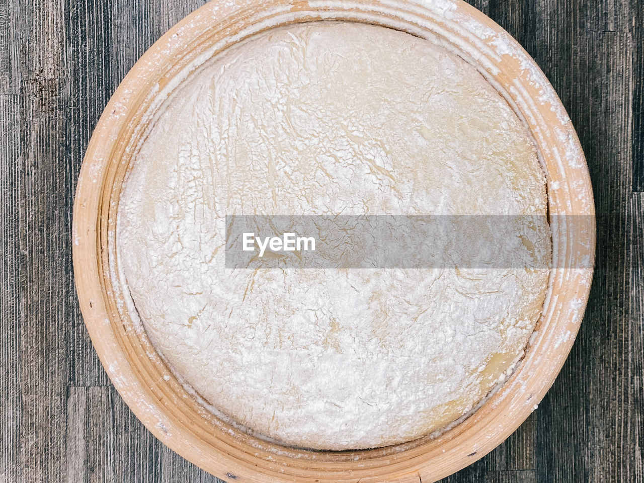 Close up from above of a rested sourdough bread in a wooden basket. 