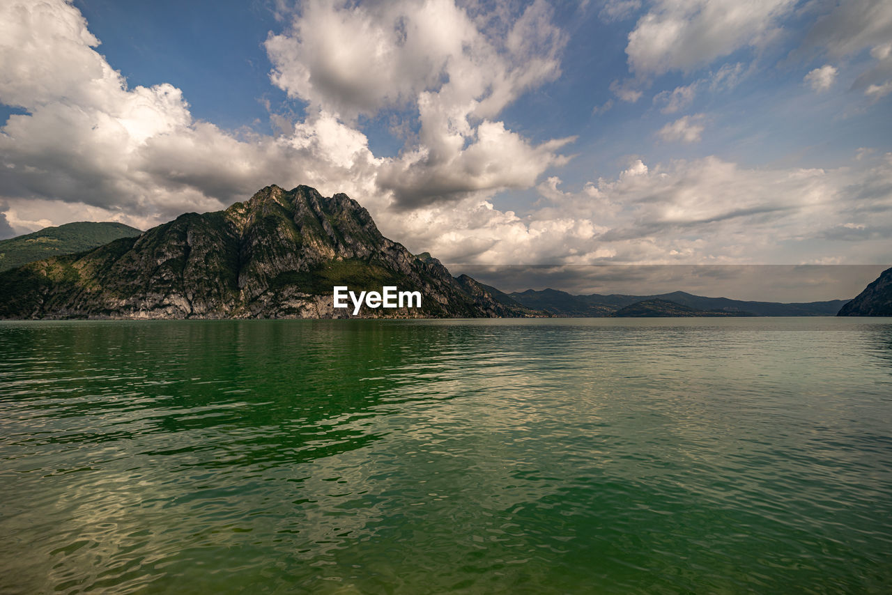 Scenic view of sea by mountains against sky