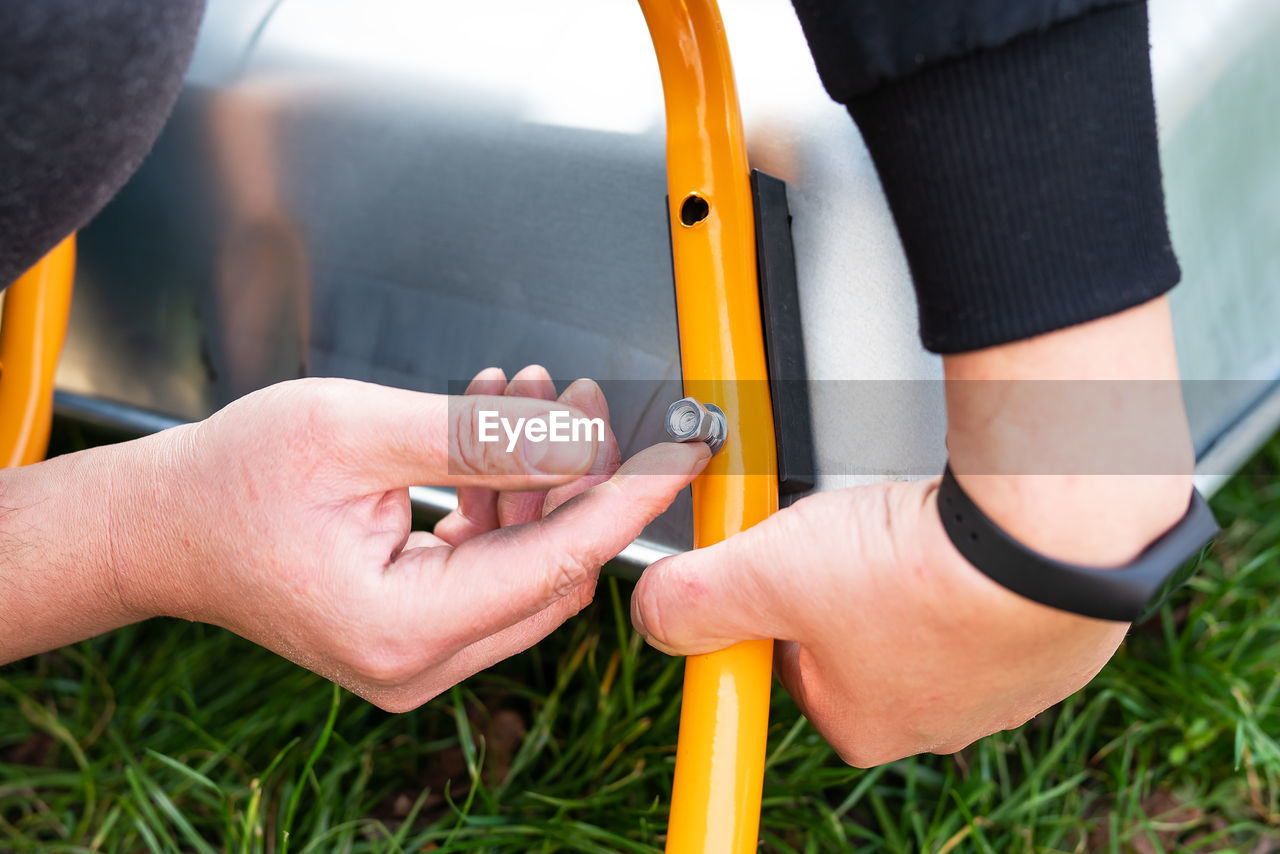 A man repairs a garden wheelbarrow, unscrews the bolts. farm work, seasonal cleaning before autumn.